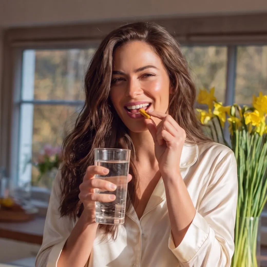 Woman taking a G-1 capsule with a glass of water